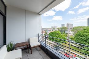Milwaukee apartment for rent - A balcony with a table and chairs overlooking a parking lot and buildings.