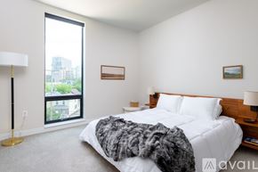 Milwaukee apartment for rent - A bedroom with a large bed and a window overlooking a cityscape.