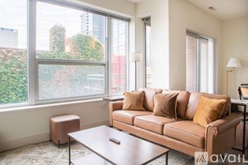 Milwaukee apartment for rent - A living room with a brown couch and a coffee table in front of a large window.