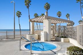 Oceanside apartment for rent - A pool area with a fence and palm trees.