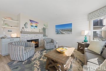 Oceanside apartment for rent - A living room with a fireplace and a painting of a beach scene on the wall.