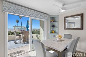 Oceanside apartment for rent - A dining room with a table set for two and a view of a pool area outside.