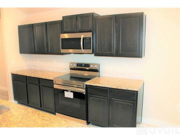 Lubbock house for rent - A kitchen with black cabinets and a granite countertop.
