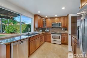 Huntington Beach house for rent - A kitchen with wooden cabinets and a stainless steel refrigerator.