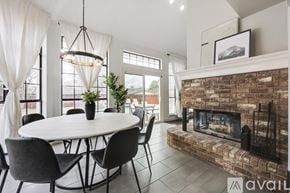 Waxahachie apartment for rent - A modern dining room with a round table and chairs, a fireplace, and a large window.