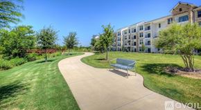 Frisco apartment for rent - A sunny day at the park with a bench and a building in the background.