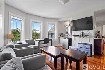 Providence apartment for rent - A living room with a grey couch, a wooden table, and a television mounted on the wall.