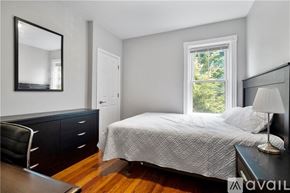 Providence apartment for rent - A bedroom with a bed, chair, and a mirror on the wall.