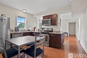 Providence apartment for rent - A kitchen with a table and chairs in the foreground and a refrigerator, microwave, oven, and sink in the background.