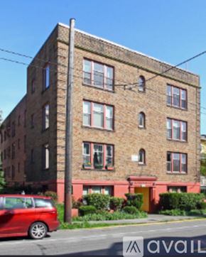 Seattle apartment for rent - A tall brick building with a red car parked in front.