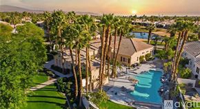 La Quinta house for rent - A sunset view of a pool surrounded by palm trees.