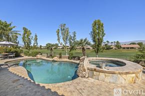 Indio house for rent - A pool surrounded by a stone patio and trees.