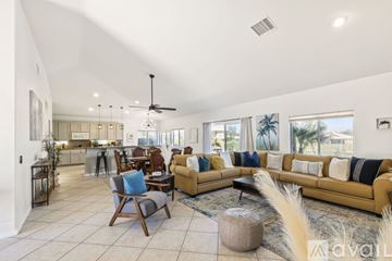 Indio house for rent - A spacious living room with a yellow sofa and a wooden chair.