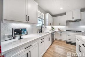 La Quinta house for rent - A modern kitchen with white cabinets and a central island with a computer on it.