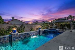 La Quinta house for rent - A pool with a waterfall and a patio area with a table and chairs.