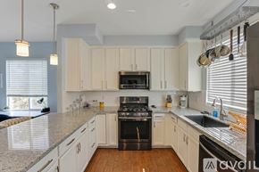 San Diego townhouse for rent - A kitchen with a black stove top oven and white cabinets.