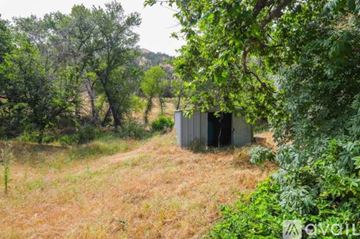Tollhouse townhouse for rent - A small building is surrounded by trees and grass.