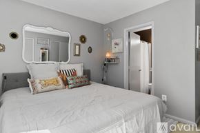 Clifton townhouse for rent - A bedroom with a white bed and a mirror above it.