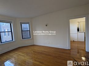 Chicago apartment for rent - A room with wooden floors and white walls, with a window on the left and a door on the right.