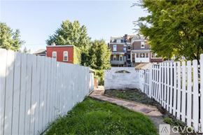 Pittsburgh house for rent - A white picket fence runs along the side of a grassy area.
