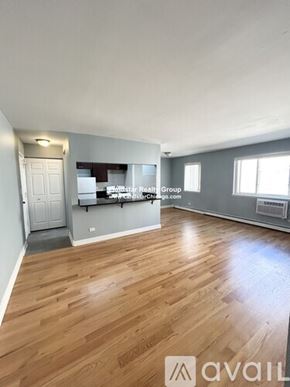 Chicago apartment for rent - A spacious room with wooden flooring and a white door.