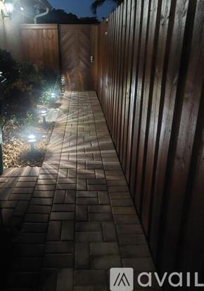 Hialeah apartment for rent - A pathway with lights on the side and a wooden fence on the other side.