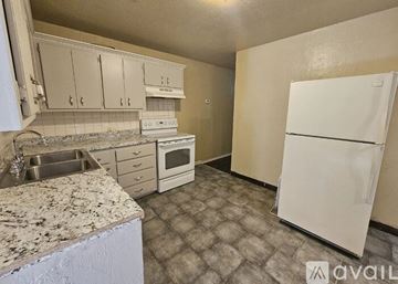 Lawton house for rent - A kitchen with a white fridge, sink, and cabinets.
