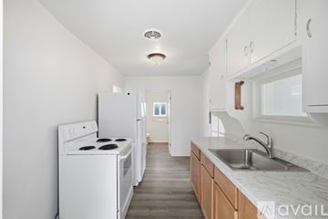 Bremerton house for rent - A white kitchen with a stove, sink and cabinets.