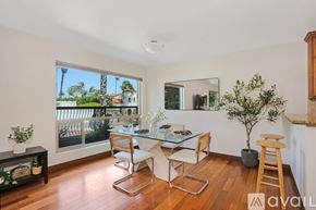 San Diego condo for rent - A dining room with a glass table and chairs, a potted plant, and a view of the outdoors through a sliding glass door.