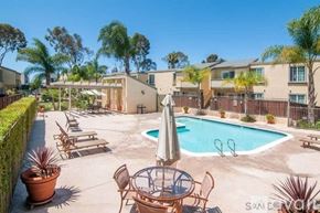 San Diego condo for rent - A pool surrounded by chairs and a table with an umbrella.