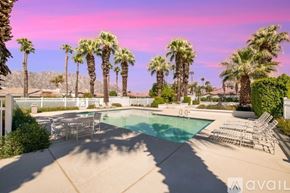 La Quinta house for rent - A pool surrounded by palm trees and lounge chairs.