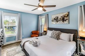 Savannah house for rent - A bedroom with a large bed, a ceiling fan, and a painting on the wall.