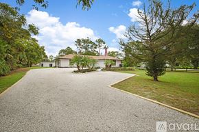 West Palm Beach apartment for rent - A house with a flag on the roof is surrounded by trees.