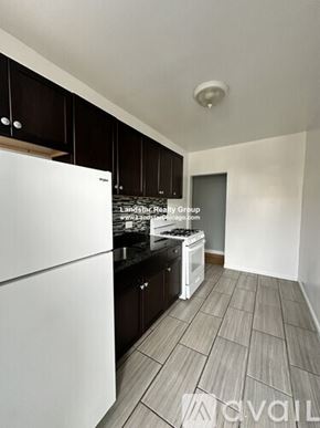 Chicago apartment for rent - A kitchen with a white fridge and black cabinets.