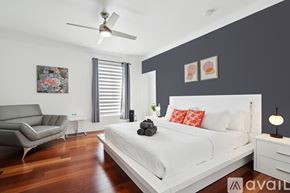 Miami house for rent - A bedroom with a white bed and a grey sofa.