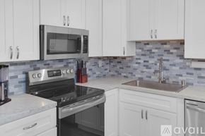 San Diego condo for rent - A kitchen with white cabinets and a black microwave above the stove.
