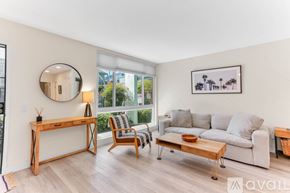 San Diego condo for rent - A living room with a grey couch, a wooden desk, a chair, and a framed picture on the wall.