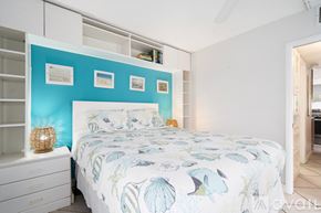 St. Pete Beach apartment for rent - A bedroom with a bed, a dresser, and a wall with pictures.