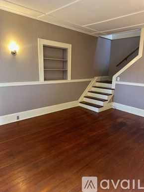 Oswego townhouse for rent - A room with wooden floors and a staircase leading to another room.