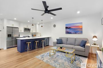 San Diego condo for rent - A modern kitchen with a bar area and a living room with a couch and a painting on the wall.