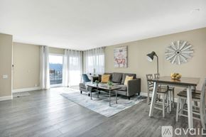 San Diego condo for rent - A living room with a grey couch, a coffee table, and a large window with curtains.