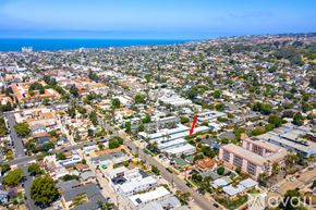 San Diego condo for rent - A bird's eye view of a city with buildings, roads, and a red arrow pointing to a specific building.
