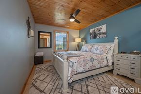 Mill Spring house for rent - A bedroom with a large bed, a ceiling fan, and a rug on the floor.
