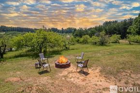 Mill Spring house for rent - A fire pit sits in the middle of a grassy field with two chairs on either side.