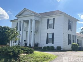 Brownsville apartment for rent - A white house with black shutters and a red brick border.