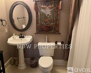 Wilson apartment for rent - A bathroom with a toilet, sink, and a tapestry hanging on the wall.