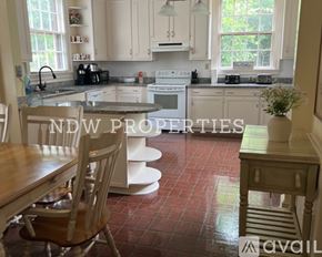 Wilson apartment for rent - A kitchen with a table and chairs in the foreground and a sign that says "NDW PROPERTIES" in the background.