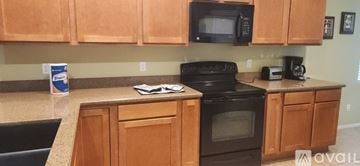 Maricopa house for rent - A kitchen with wooden cabinets and a black stove top oven.