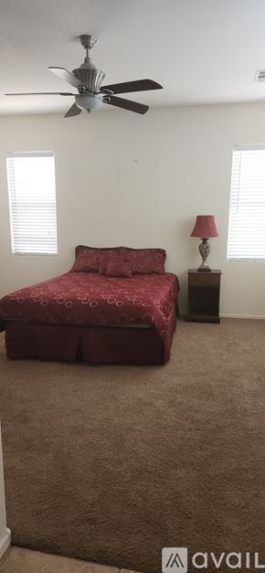 Maricopa house for rent - A bedroom with a red bedspread and a ceiling fan.