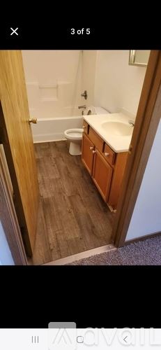 Waterloo house for rent - A bathroom with a toilet, sink, and wooden floors.